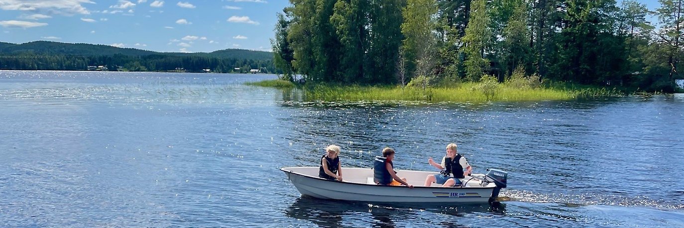 Tre barn som kör liten motorbåt